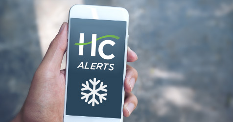 Hand holding cellphone will HC Text Alert Icon