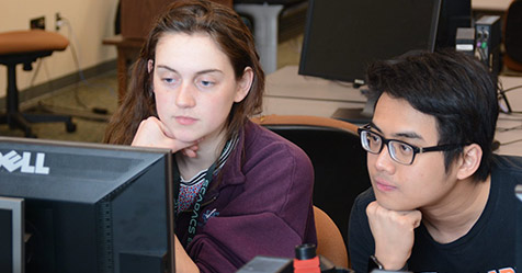 Photo of two students looking at a computer screen