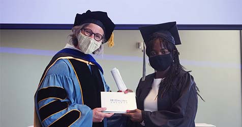 Vice President Emily Lardner gives a diploma cover to a graduate.