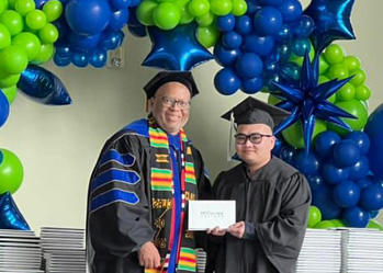 Highline College President John Mosby gives a diploma cover to a graduate.
