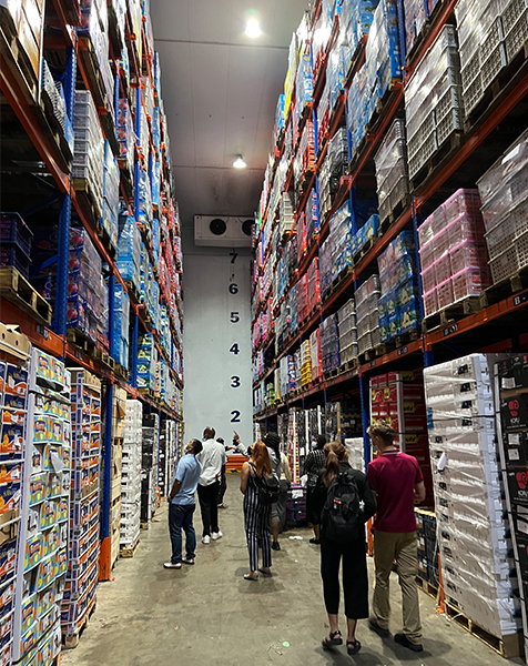 Students look up at boxes of fruit in a cold storage warehouse.