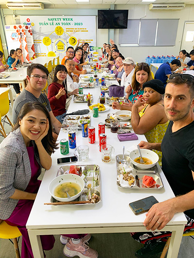 Group of students and college employees eat at a table in Vietnam.